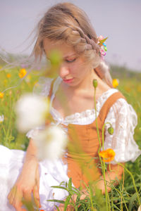 Close-up of girl holding flowers on field