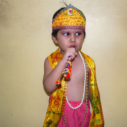 Portrait of cute girl standing against wall