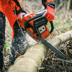 Man holding a chainsaw and cut trees. lumberjack at work. gardener working in the forest. 