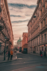 People walking on road against buildings in city