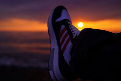 Low section of person against sea during sunset