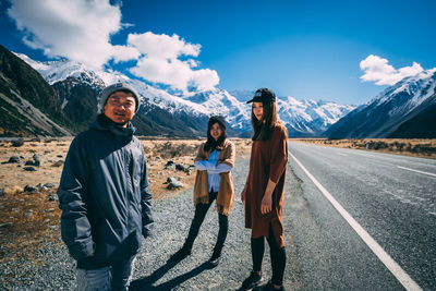 Full length of friends standing on road against sky