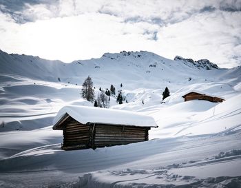 Scenic view of shack on snow covered mountains against sky