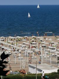 Sailboats in sea by city against sky