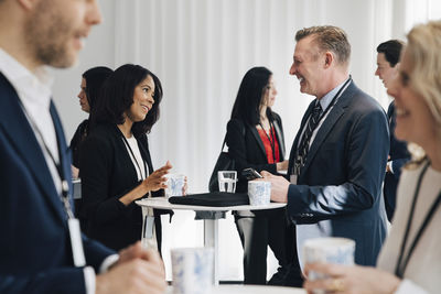 Smiling female entrepreneur talking to mature colleague at table in office seminar