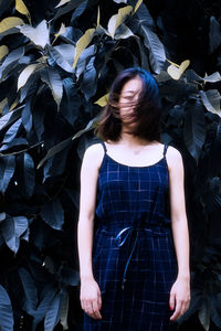 Portrait of young woman standing against plants