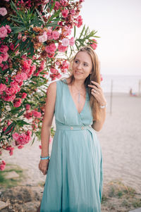 Portrait of young woman standing against trees