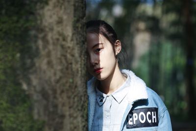 Close-up of young woman against blurred trees