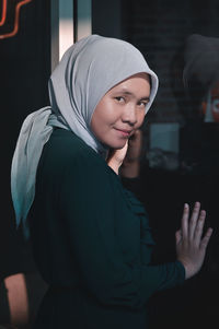 Portrait of smiling young woman by window