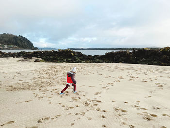 Rear view of man on beach against sky