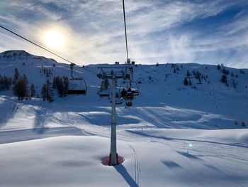 Ski lift over snowcapped mountains against sky