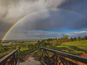 Scenic view of rainbow over field against sky