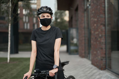 Coronavirus pandemic woman in helmet and mask on bicycle in city in evening, pandemic