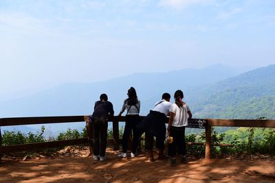 Rear view of people looking at mountains against sky