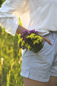 Midsection of woman holding bouquet in pocket