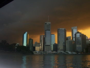 Modern buildings by river against sky in city