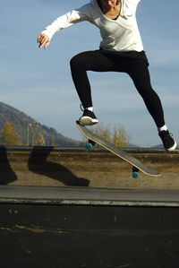 Low section of man skateboarding on road