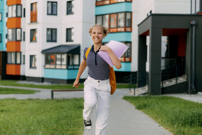 Portrait of young woman standing on footpath in city