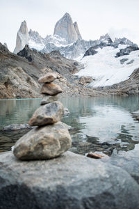 Stack of rocks by lake against snowcapped mountains and glacier