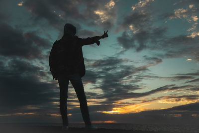 Silhouette man standing by sea against sky during sunset