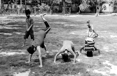 Friends practicing handstand on field