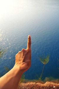 Close-up of person gesturing against lake