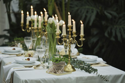 View of dining table with candles against plants