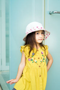 Happy girl standing against yellow wall