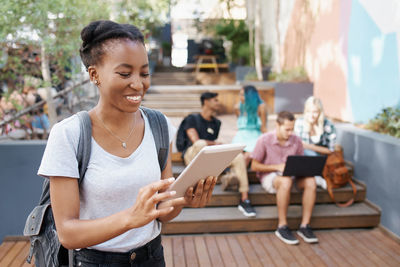 Young woman using digital tablet with friends in background