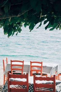 Empty chairs and tables by sea