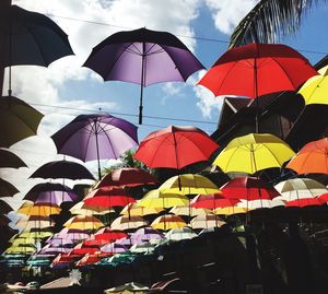 Low angle view of colorful umbrellas hanging against sky in city