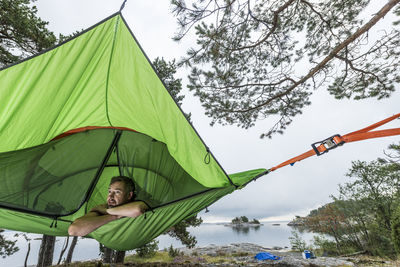 Man resting in hammock at lakeshore