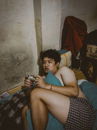 Young man sitting on sofa against wall