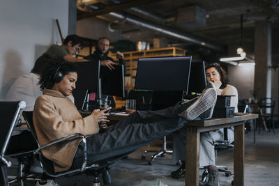 Female entrepreneur using smart phone by computer programmers working at office