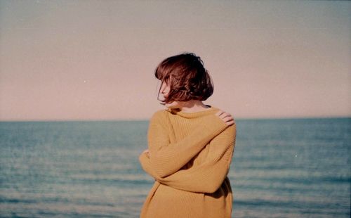 Rear view of man standing at beach against clear sky