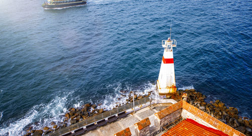 High angle view of lighthouse by sea against buildings