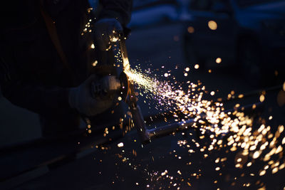 Sparks from grinding metal. steel processing in workshop. lights in dark. production of parts.