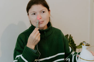 A young girl treats her nose with an infrared light device.