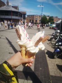 People holding ice cream cone on street in city