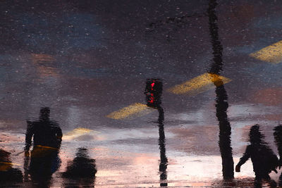 Reflection of sky in puddle on street at night