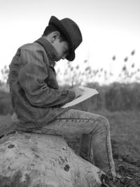 Side view of boy sitting on rock