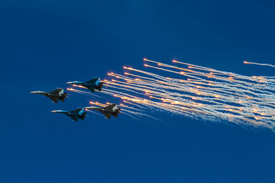 Low angle view of airplane flying against clear blue sky