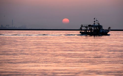 Ship sailing on sea against sky during sunset