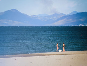 People standing at beach against sky