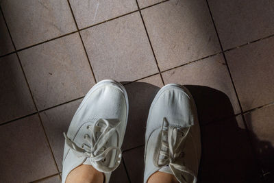 Low section of man standing on tiled floor