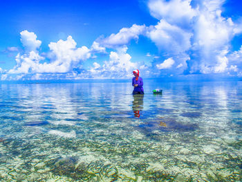 Woman standing on beach against cloudy sky