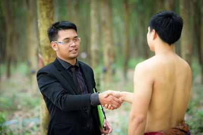Manager handshaking with shirtless worker on field