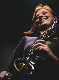 Smiling young woman playing guitar