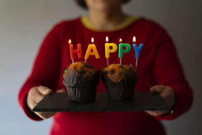 Woman taking a plate with lit candles that form the word happy.