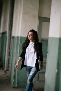 Portrait of beautiful young woman standing against wall